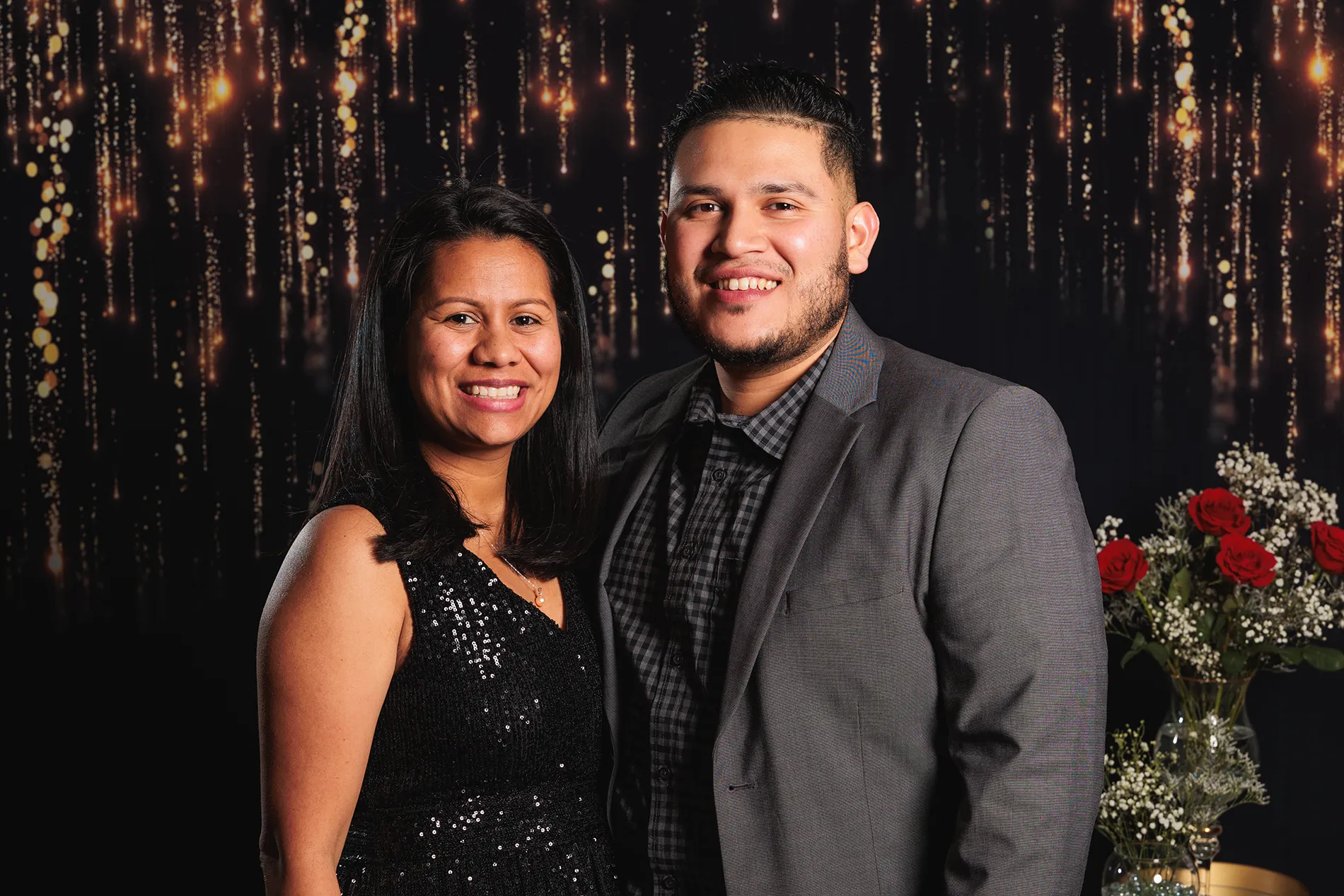 Couple posing together in elegant attire with a dark gold backdrop, photographed inside a church in Monticello, NY.