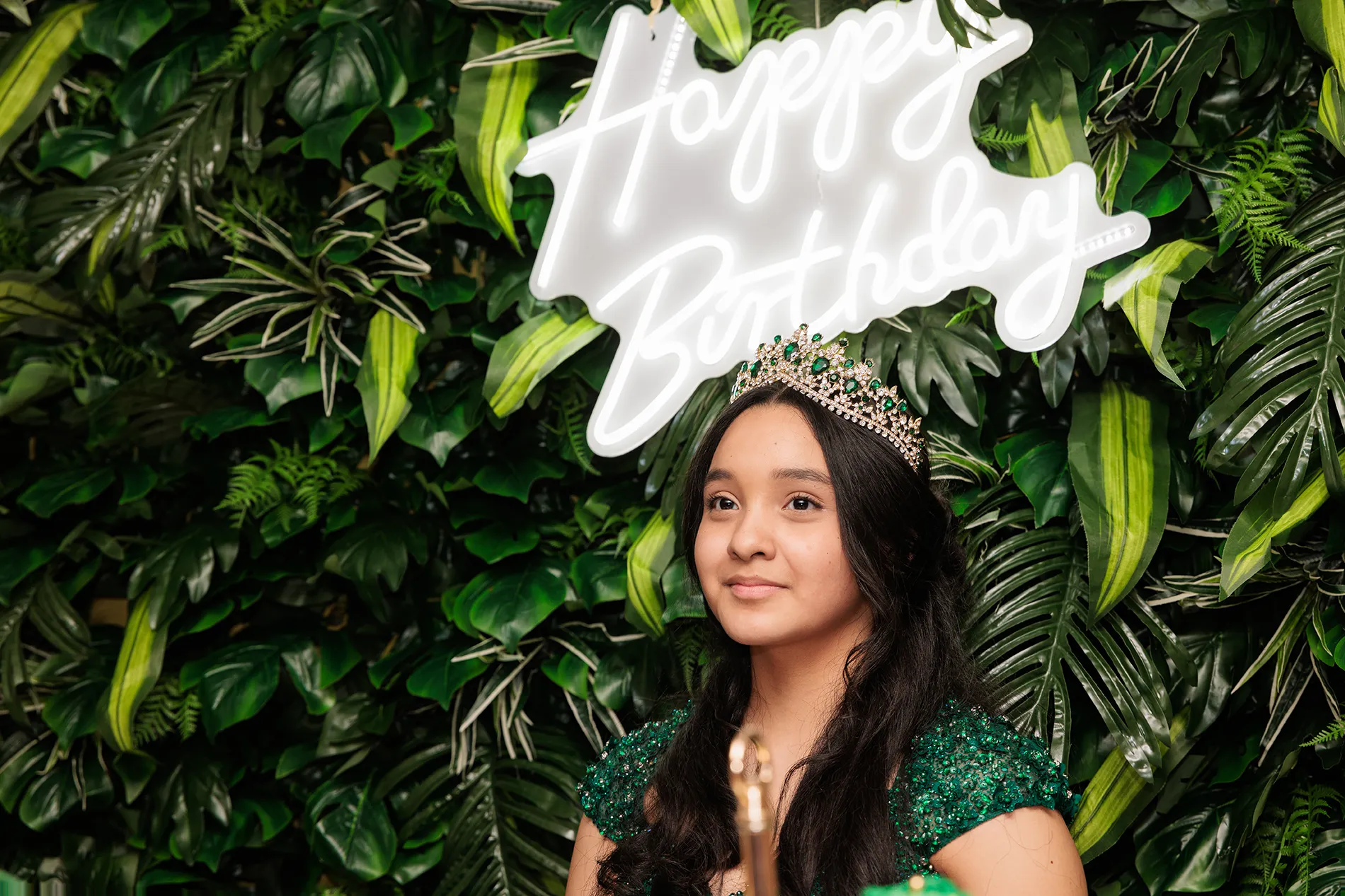 Sweet 16 portrait in Jeffersonville NY — quinceañera Elizabeth posing in a green dress with a tiara under a ‘Happy Birthday’ sign | Retrato de quinceañera en Jeffersonville NY con vestido verde y corona.
