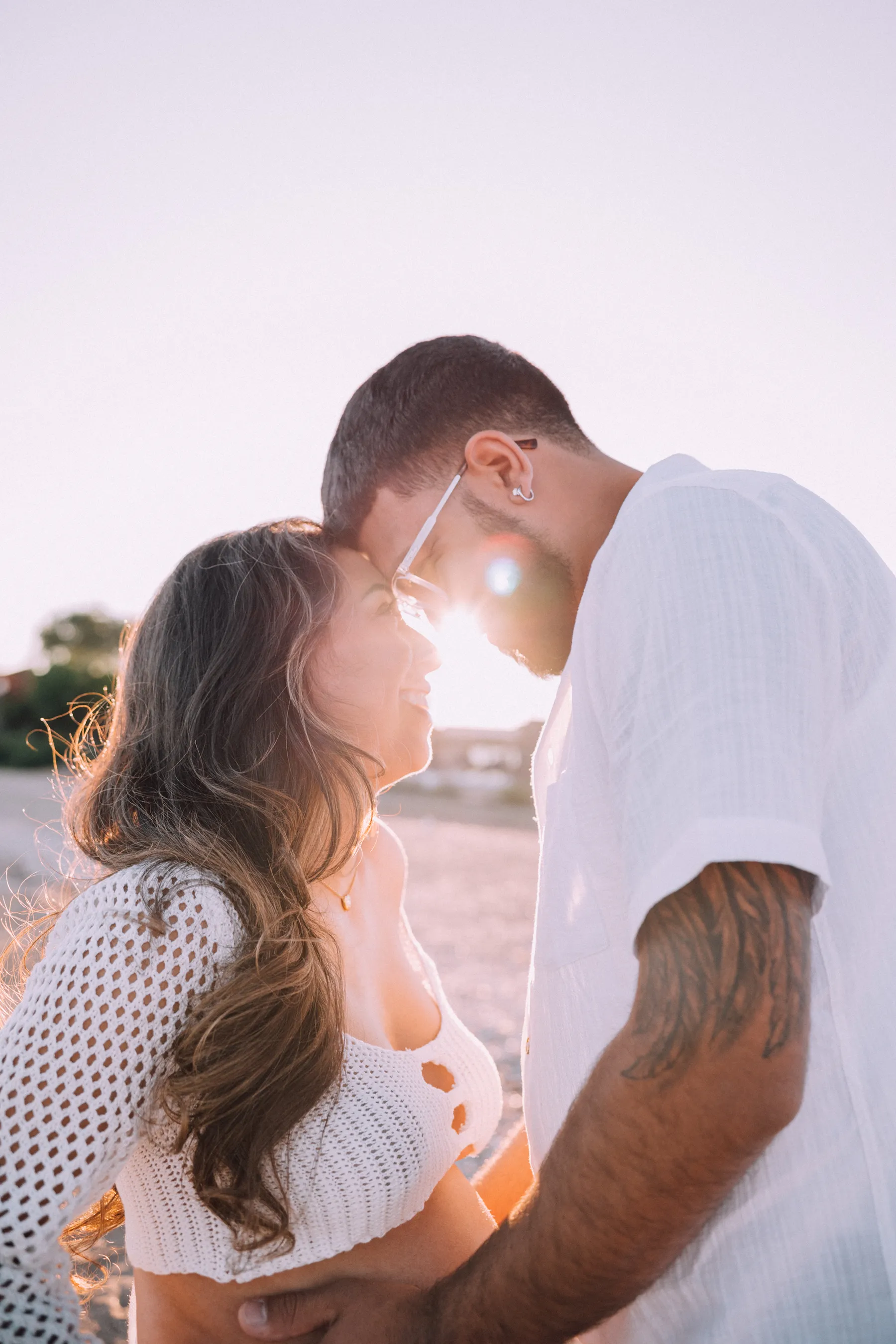 Couple standing close on the beach at sunset during a maternity session in New Haven, CT.