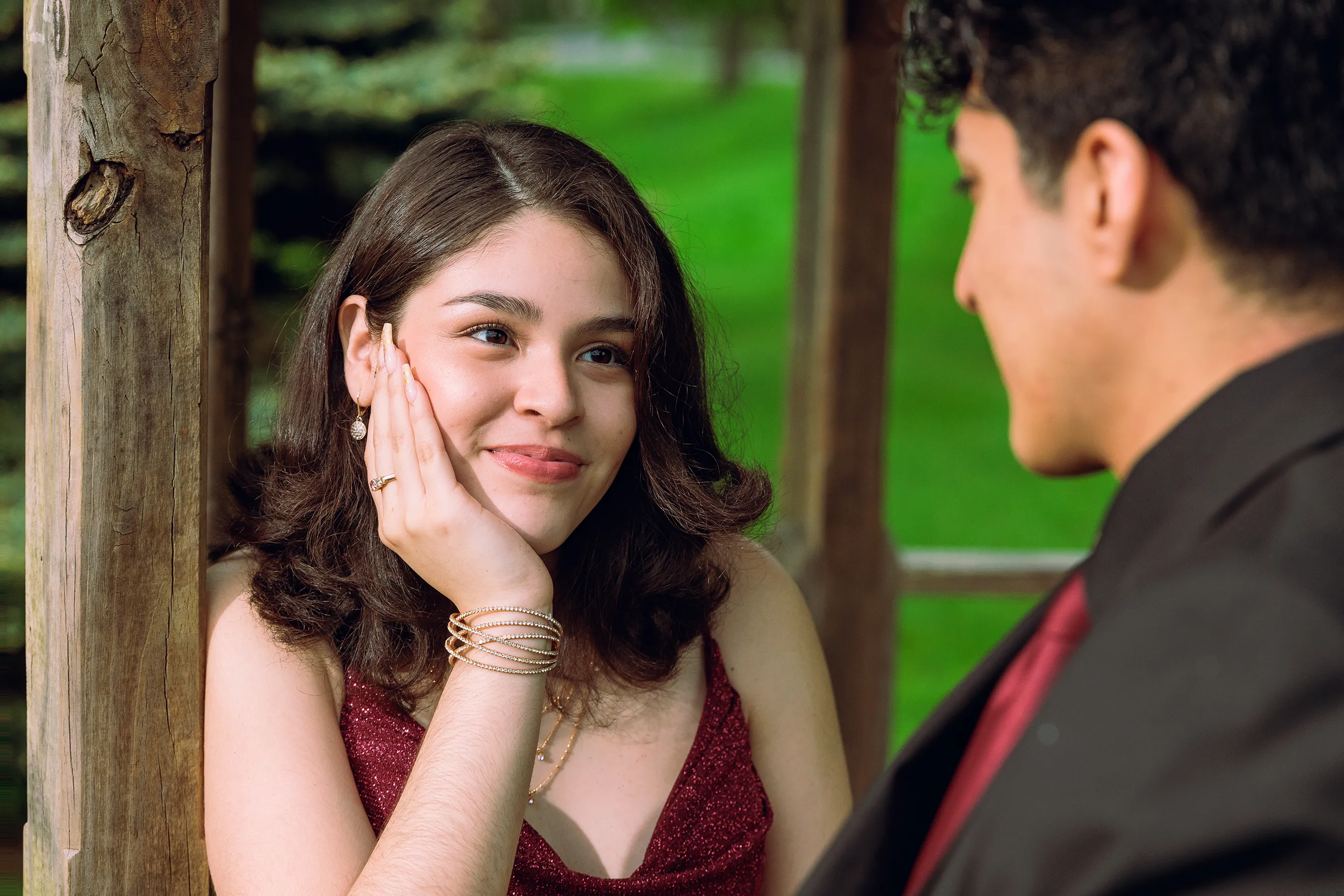 Young woman smiling lovingly at her partner while sitting in a gazebo during a portrait session for prom in Monticello, NY.